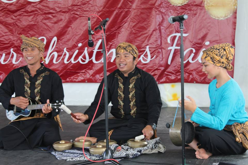 Five talempong (in the middle) are being played with two wooded sticks